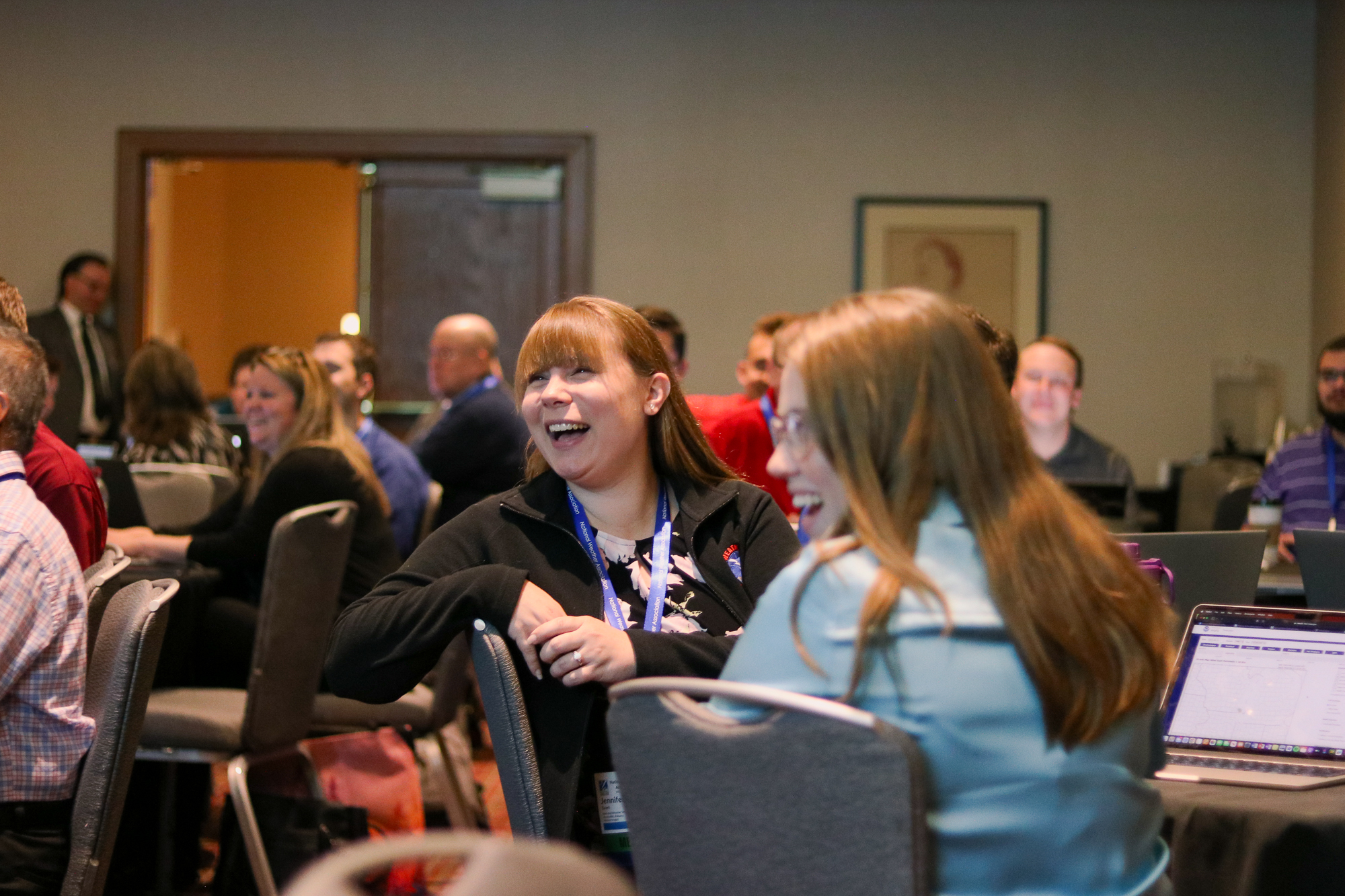 Participants laughing in a crowded room.